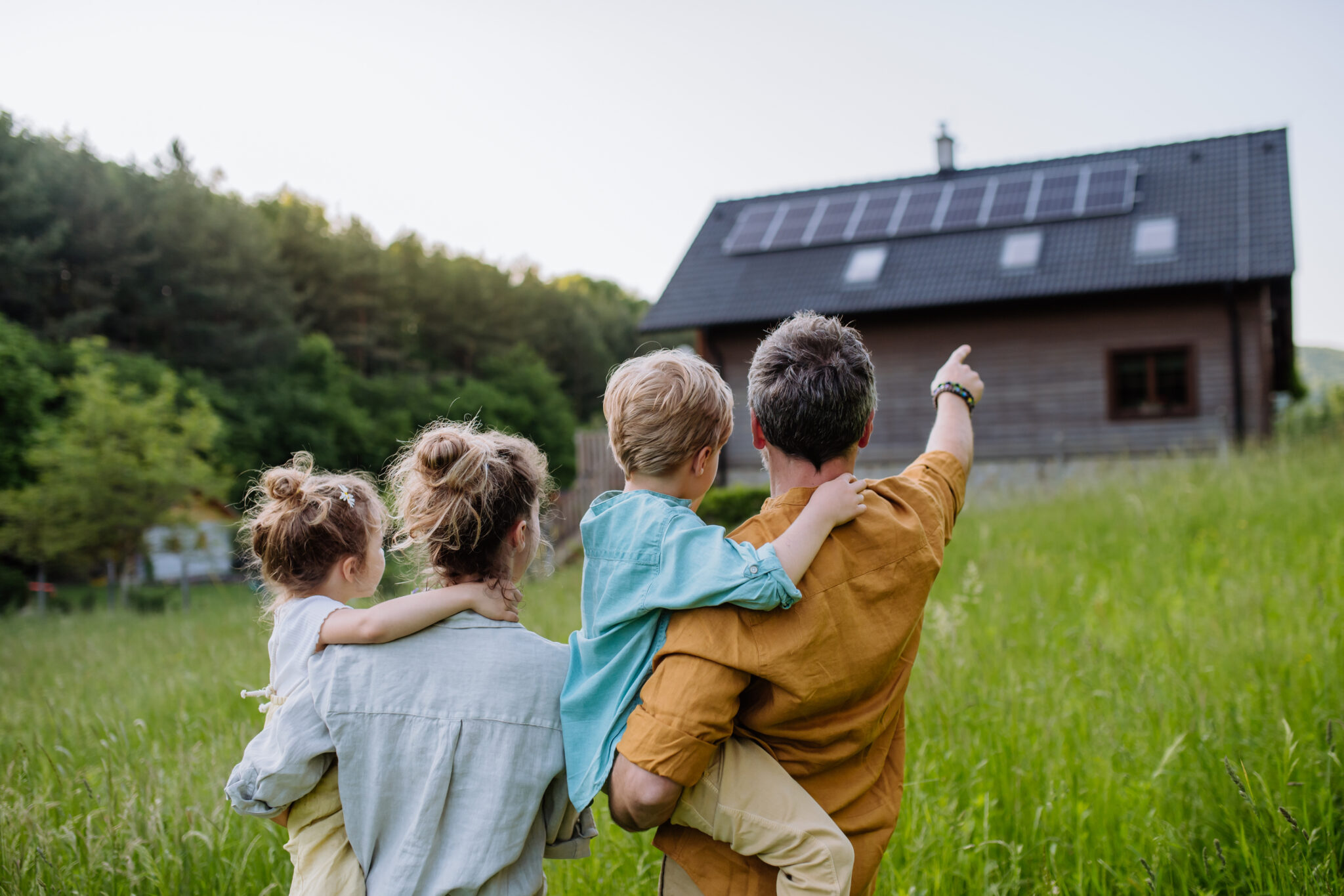 Famille devant sa maison avec des panneaux photovoltaïques profitant de la garantie à vie ISOFORLIFE